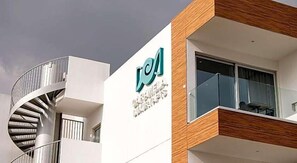 Ein modernes Gebäude mit einer Wendeltreppe, einem Balkon mit Glastrennwand und einem Schild mit dem Logo und dem Namen 'CAMPUS'.