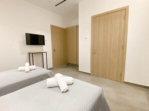 Habitación de hotel con dos camas, televisión y armarios de madera.