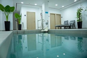 Ein moderner, überdachter Pool mit großen Glaswänden, Holztüren und Topfpflanzen.
