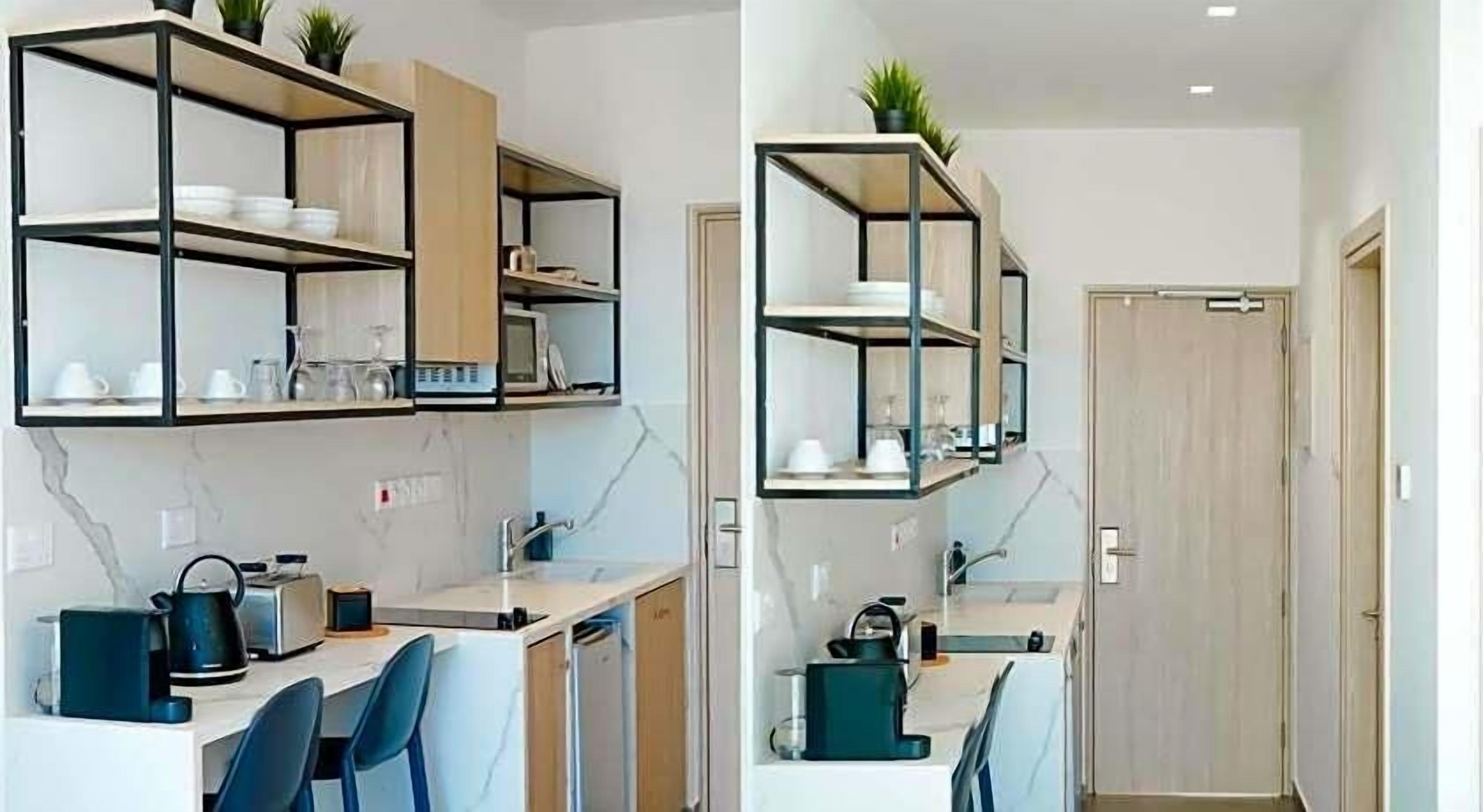 A modern kitchen with built-in shelves, a dining area with chairs, and a door leading to another room.