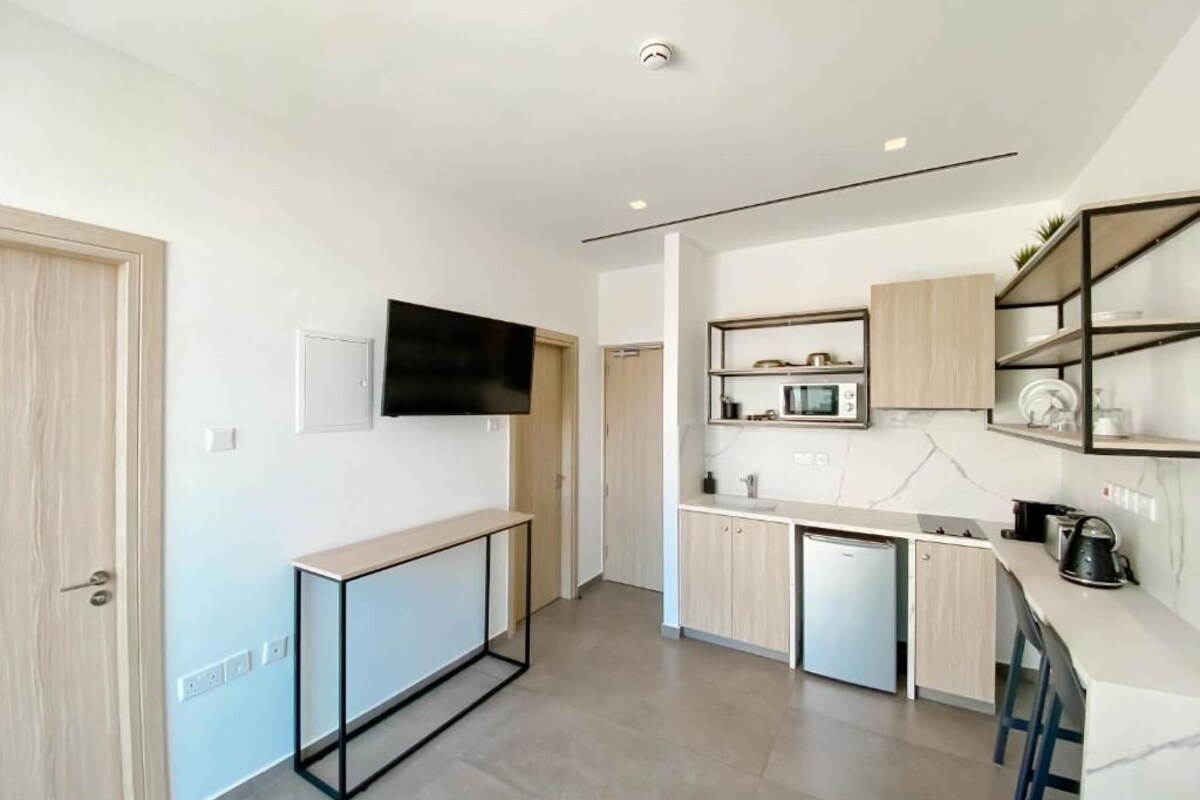 A modern kitchen with a built-in microwave, a coffee machine, and a small refrigerator.