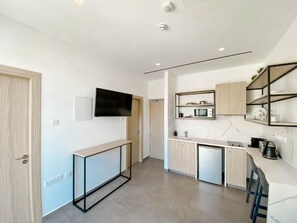 Una cocina moderna con microondas integrado, cafetera y un refrigerador pequeño.