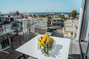 A balcony with a table featuring fruits and a clear view of the cityscape and ocean. - Caramela Luxury Apartments (Ayia Napa)