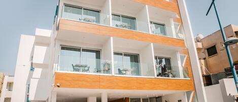 Un edificio moderno de varios pisos con balcones, ventanas amplias y techo plano.