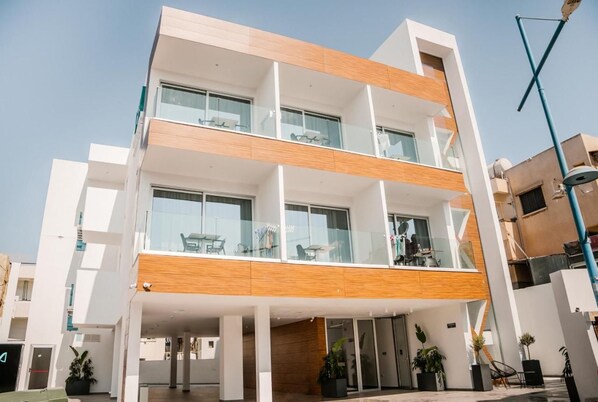A modern multi-story building with balconies, large windows, and a flat roof. - Caramela Luxury Apartments (Ayia Napa)