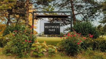 A sign for Westwood Park surrounded by lush greenery and flowering plants.