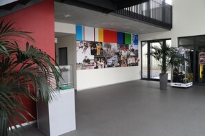 Un hall d’entrée moderne avec un mur d’accent rouge, un grand photomontage et un comptoir d’accueil.