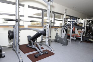 Une salle de sport équipée de divers appareils d’exercice, notamment un banc de développé couché, des appareils de musculation et des appareils de cardio.