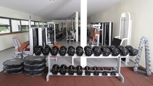 Un gimnasio con equipo de ejercicio variado, incluyendo mancuernas, discos de pesas y una banca.