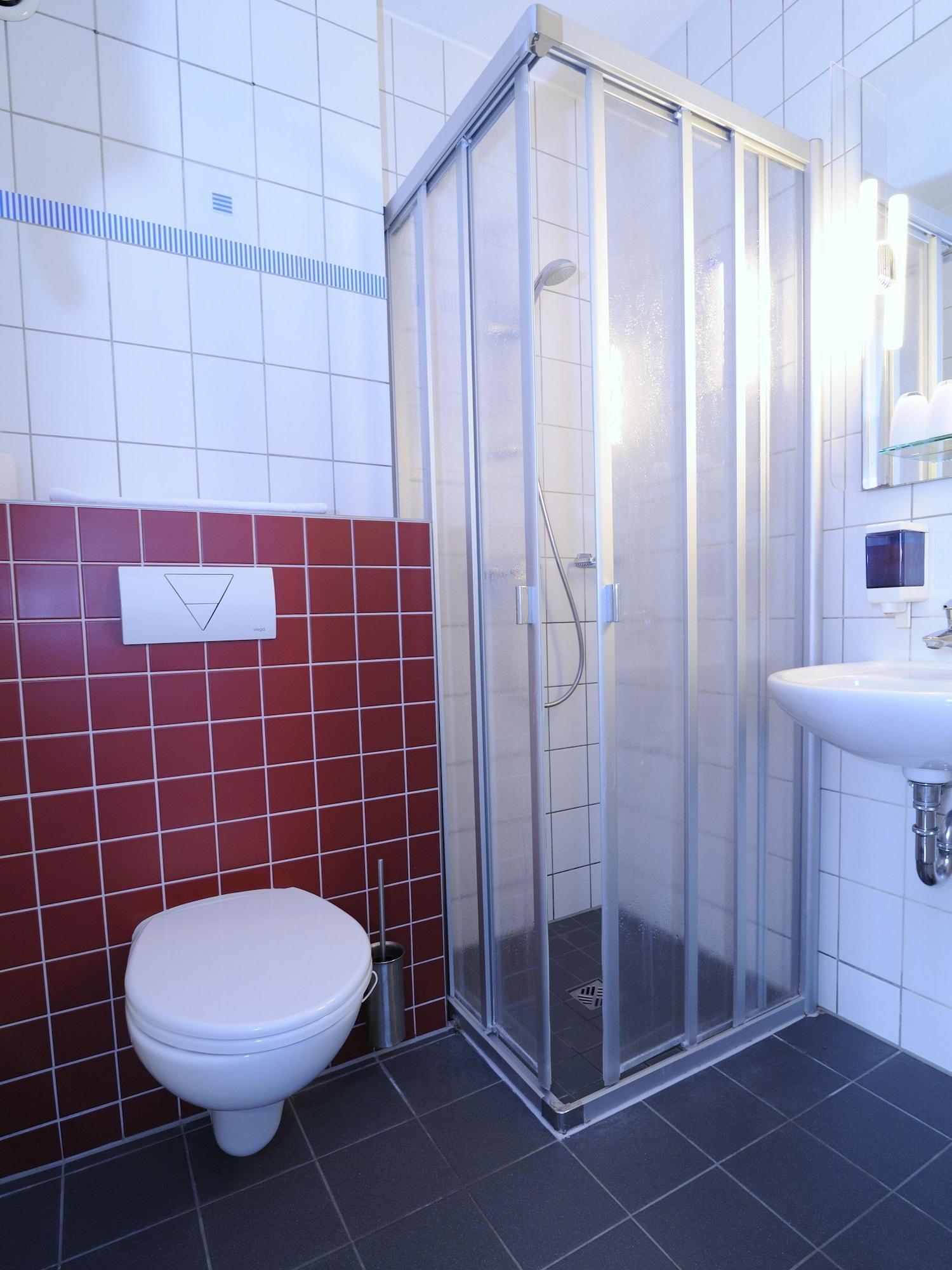 Un baño moderno con ducha de vidrio, inodoro blanco y lavamanos.