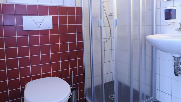 Un baño moderno con ducha de vidrio, inodoro blanco y lavamanos.