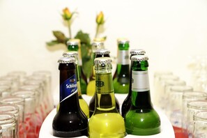 Varias botellas de cerveza sobre una mesa, con vasos al fondo.