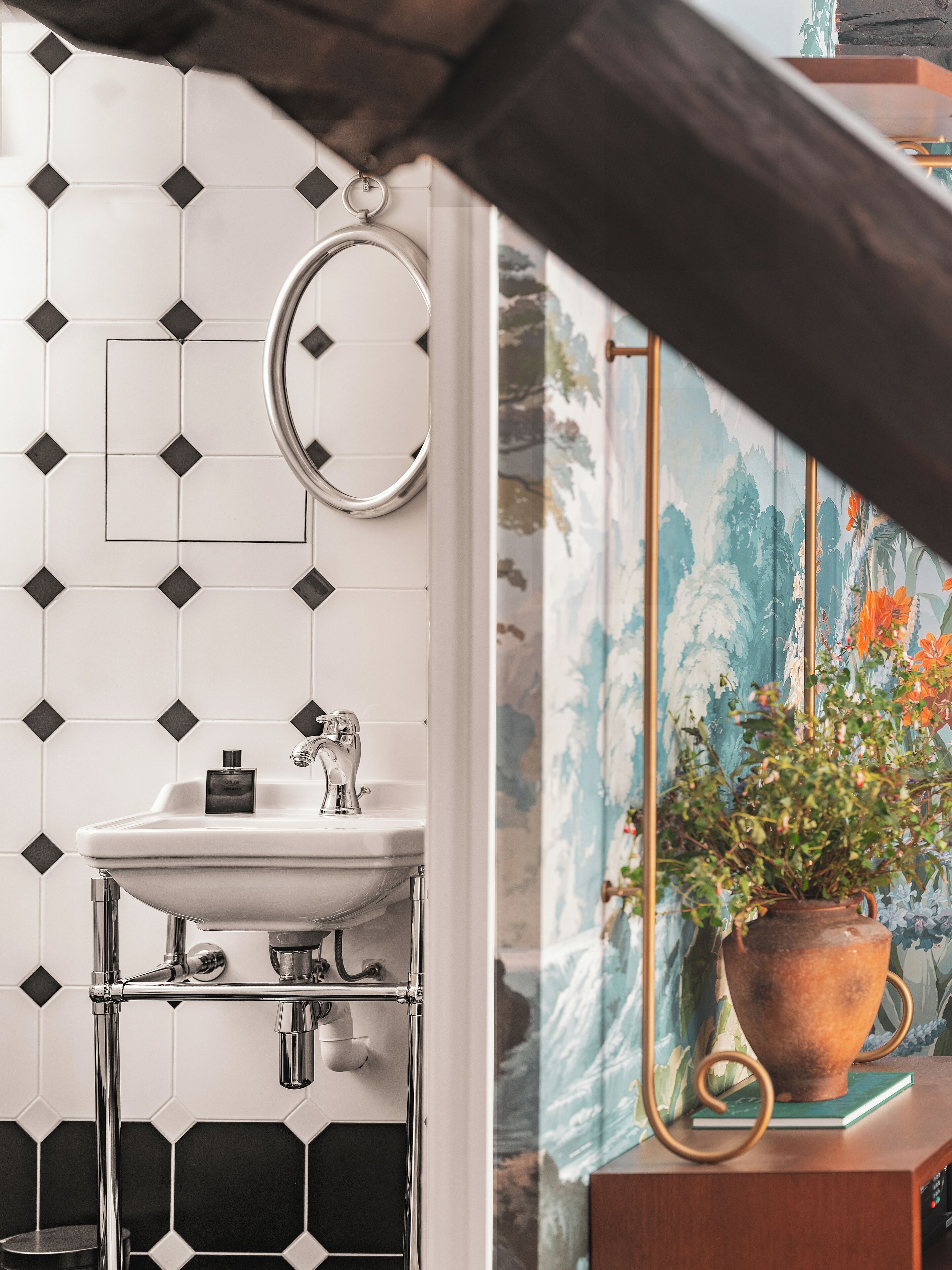 Un baño con lavamanos blanco, grifería cromada y un espejo decorativo.