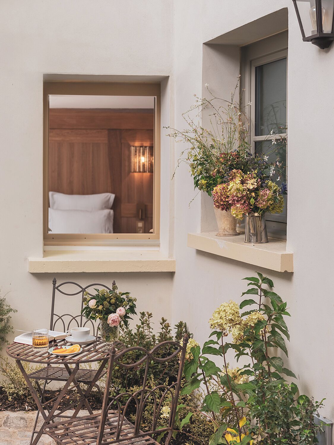 Una habitación acogedora con una cama, un ventanal con vistas y una mesita con una bebida y un plato.
