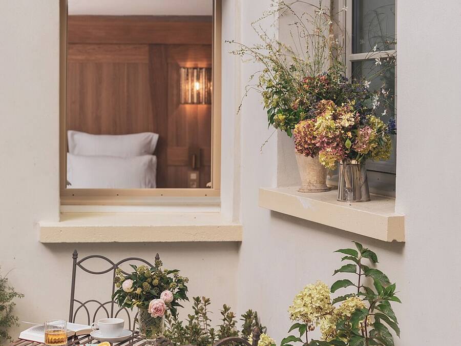 Una habitación acogedora con una cama, un ventanal con vistas y una mesita con una bebida y un plato.