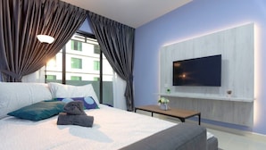 A modern hotel room with a large bed, a flat-screen TV mounted on the wall, a small table with a vase of flowers, and a window with curtains.