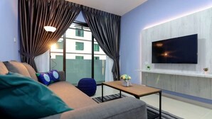 A modern living room with a sofa, a coffee table, and a flat-screen TV mounted on the wall.