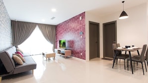 A modern living room with a sofa, TV, and dining area. - Modern, High Floor Suasana Suites 05 in JB (Johor Bahru)