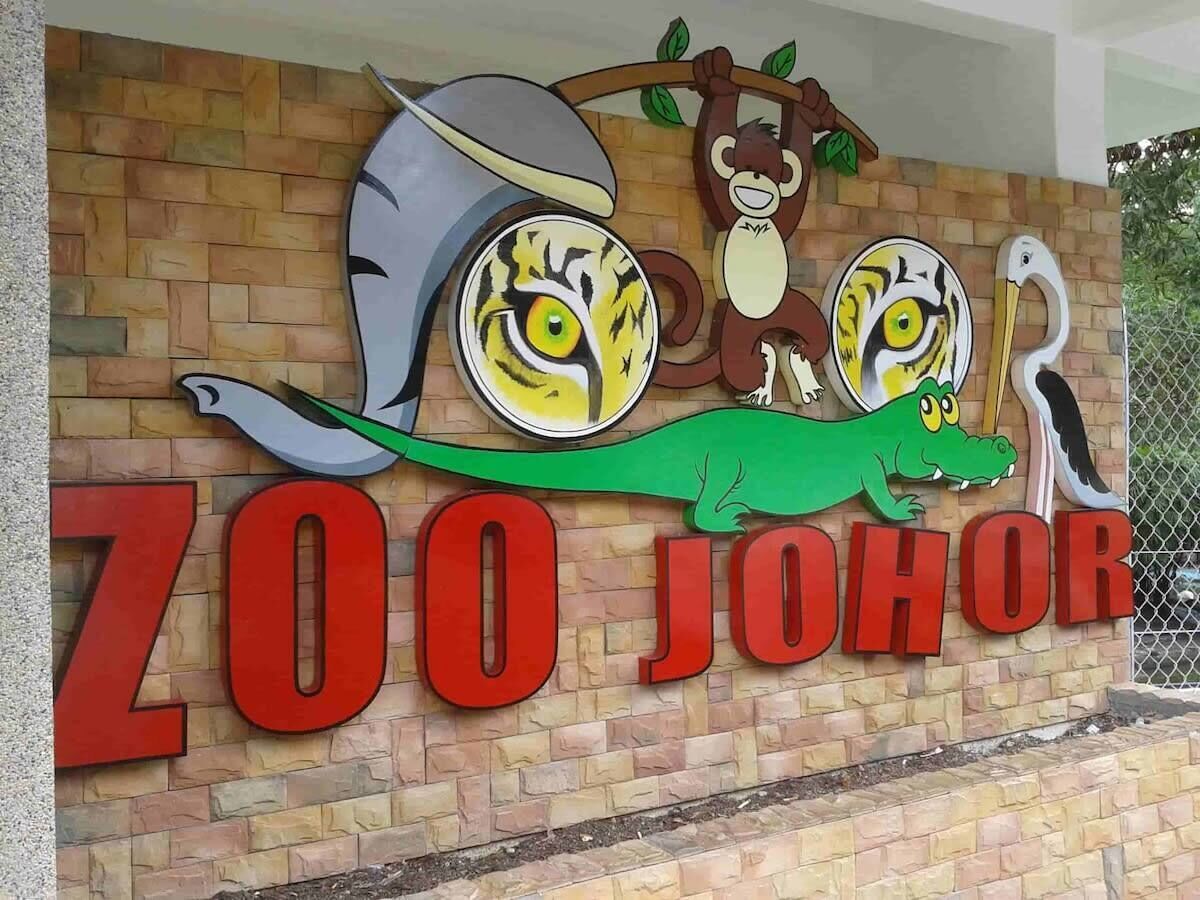 A zoo sign with a tiger, a monkey, and a crocodile illustration.