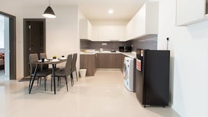 A modern kitchen with a dining area, a washing machine, and a refrigerator. - Modern, High Floor Suasana Suites 05 in JB (Johor Bahru)