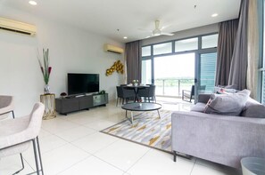 A modern living room with a flat-screen TV, a dining table, and a sofa.