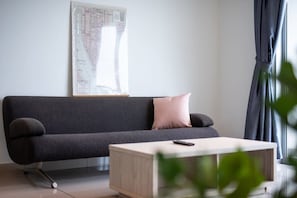 Una sala de estar moderna con un sofá gris oscuro, una mesa de centro de madera clara y un mapa en la pared.