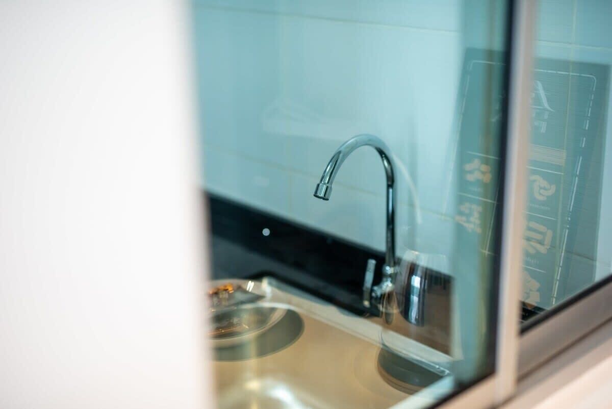 A modern bathroom with a glass-enclosed sink and a chrome faucet.