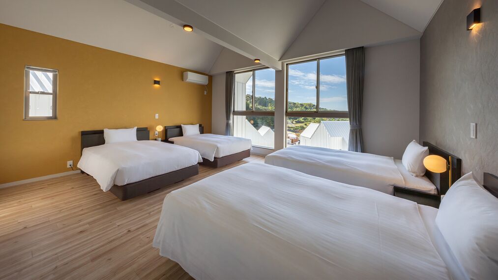 A hotel room with two beds, a large window with a view, and a wooden floor.
