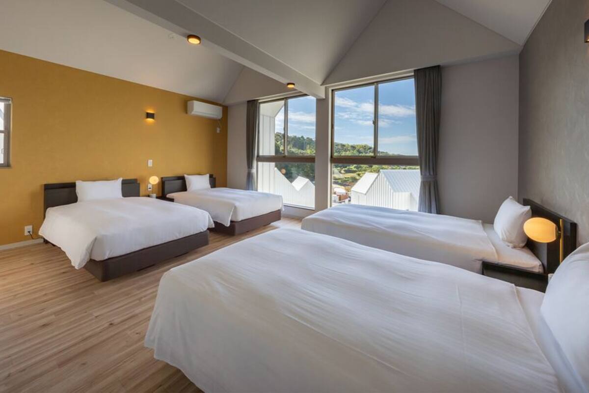 A hotel room with two beds, a large window with a view, and a wooden floor.