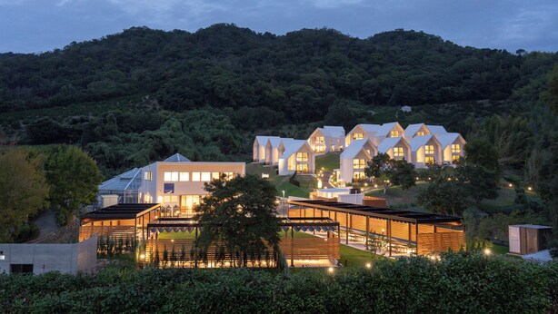 A modern hotel with multiple white-roofed buildings, a glass-roofed structure, and a well-lit entrance area. - Kanatanosato (Wakayama)