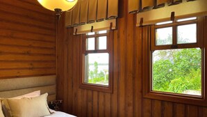 A wooden-paneled room with a bed, two windows, and a hanging lamp. - Kastel Konak Hotel (Surmene)