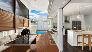 Una cocina moderna con una isla grande, un comedor con vista a la piscina y una zona de estar acogedora con una parrilla.