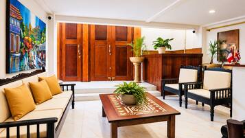 A spacious living area with a sofa, chairs, a coffee table, and a wooden wardrobe.