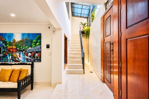 Un vestíbulo de hotel con una escalera, un cuadro, un sofá con cojines y una puerta de madera.