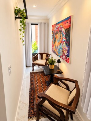 A hallway with a seating area, a colorful abstract painting, and a potted plant. - Residence Pipa Beach (Tibau do Sul)