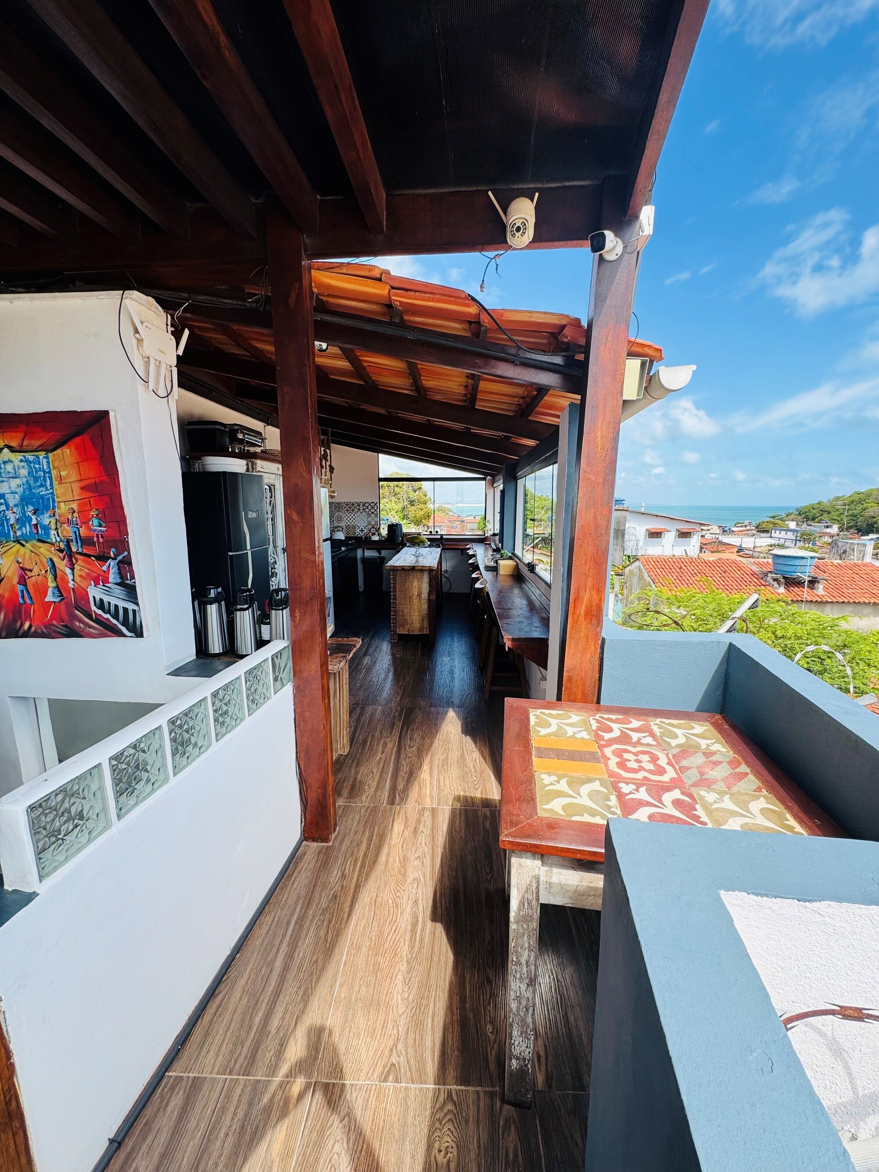 Un espacio al aire libre techado con techo de madera, una mesa de comedor y vista al mar.