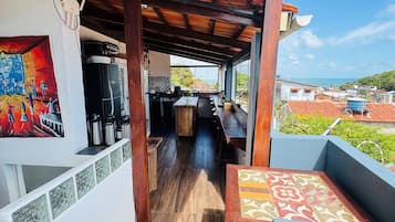 Un'area esterna coperta con tetto in legno, un tavolo da pranzo e vista sul mare.