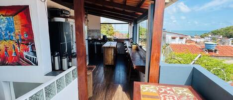 Un espacio al aire libre techado con techo de madera, una mesa de comedor y vista al mar.