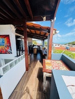 Un espacio al aire libre techado con techo de madera, una mesa de comedor y vista al mar.