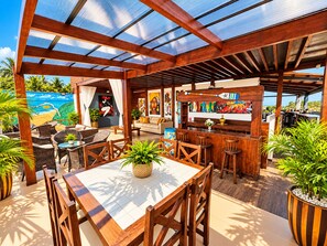 An outdoor patio area with wooden furniture, a bar, and a mural on the wall. - Residence Pipa Beach (Tibau do Sul)