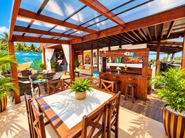 Un espacio al aire libre con patio, mobiliario de madera, una barra y un mural en la pared.