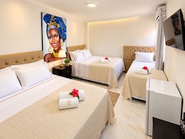 Una habitación de hotel con tres camas, un televisor y un retrato grande en la pared.