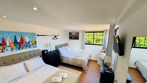 A hotel room with two beds, a television, a painting, and a window with a view of greenery. - Residence Pipa Beach (Tibau do Sul)