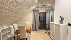 A compact, modern room with a sloped ceiling, a dining table with chairs, a radiator, a cabinet, and a potted plant. - H&H HOME - Cosy Rooftop Apartment with Loggia (Sindelfingen)