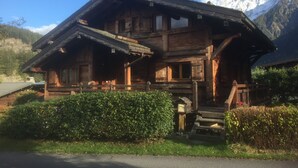 A wooden chalet with a steep roof, a porch, and a staircase leading to the entrance.