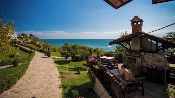A patio area with a stone pathway leading to a seating area overlooking a body of water. - MONASTERY Apart Complex (Sveti Vlas)