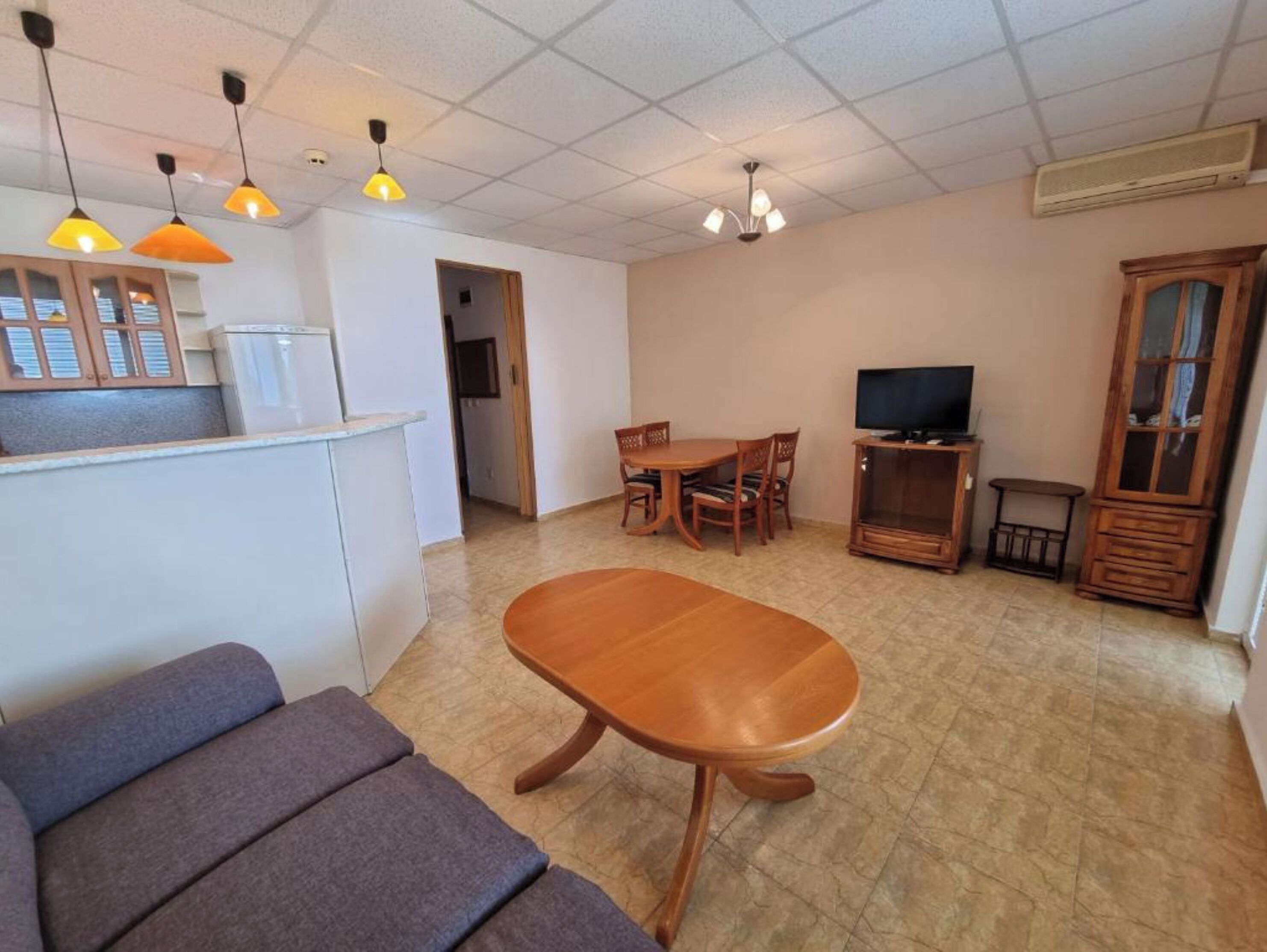 A living room with a sofa, a dining table, and a TV.