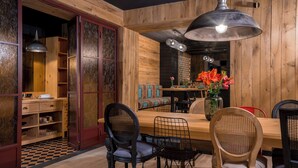 A wooden dining area with a long table, chairs, and a hanging light fixture.
