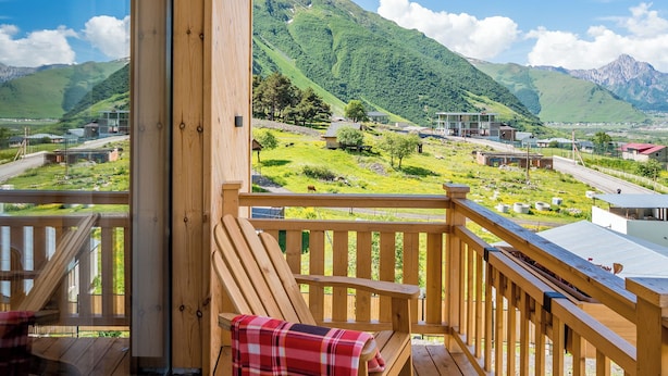 A wooden deck with a bench and a table, overlooking a mountainous landscape.