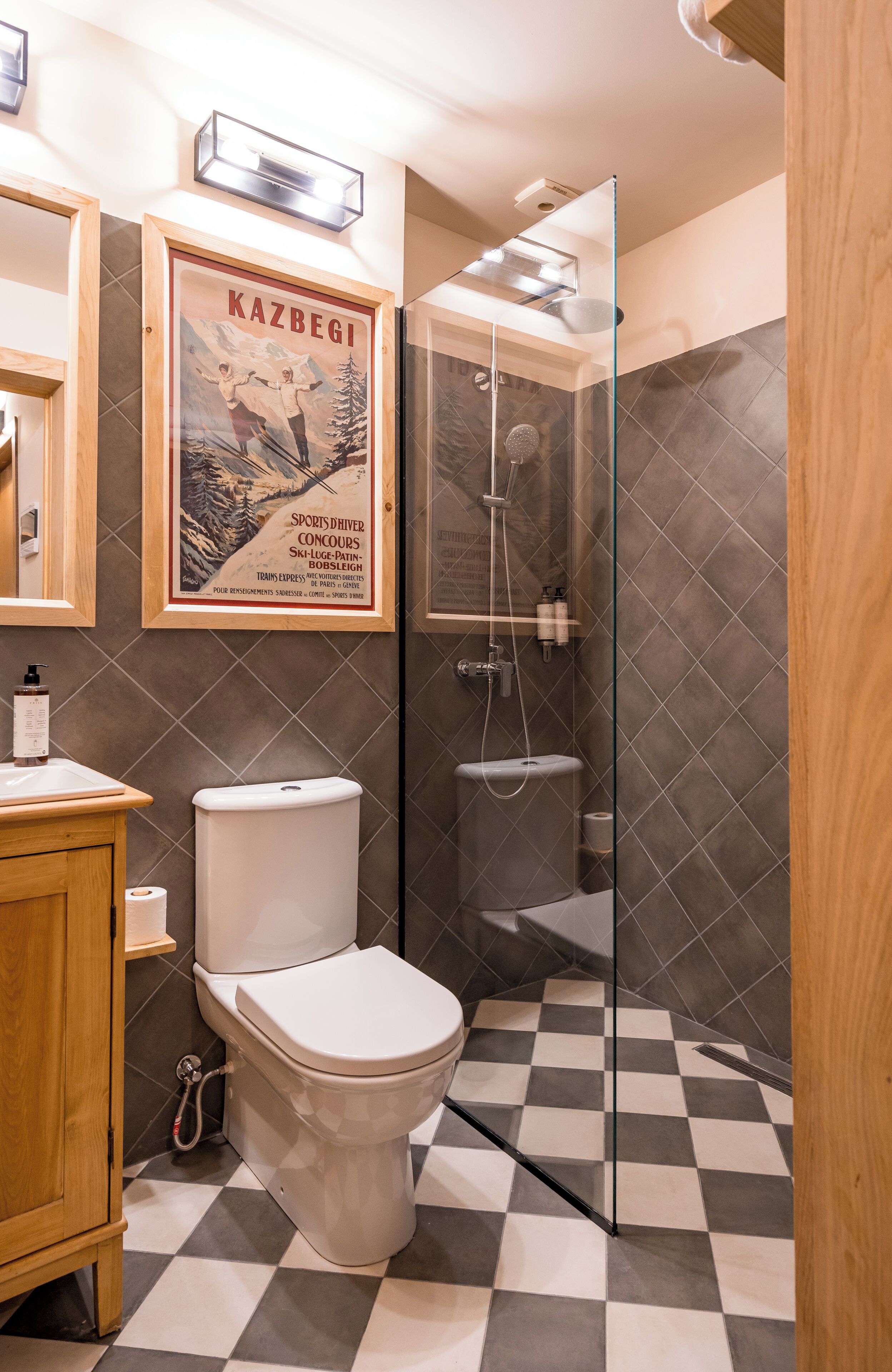 A bathroom with a toilet, a shower, and a checkered floor.